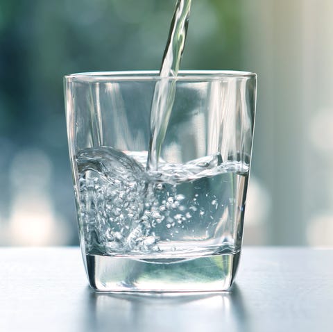 Close up the pouring purified fresh drink water from the bottle on table in living room