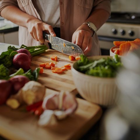 closeup of young female hands chopping fresh vegetables on chopping board while in modern kitchen   preparing a healthy meal to boost immune system and fight off coronavirus