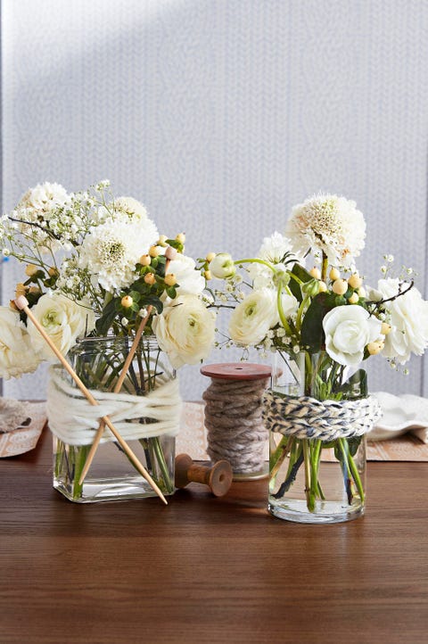 plain glass vases wrapped with strands of yarn and knitting needles