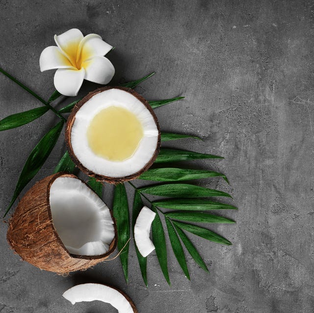 Fresh melted coconut oil in half of nut on table Fresh melted coconut oil in half of nut on table