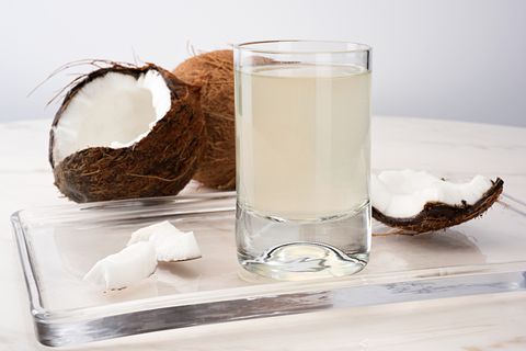 coconut water in a glass next to a cracked coconut