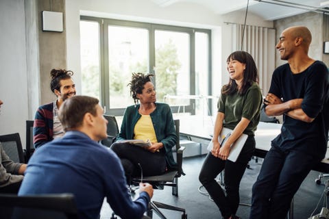 Colleagues looking at cheerful businesswoman in meeting colleagues looking at cheerful businesswoman in meeting