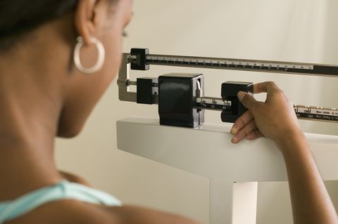 Woman on scale adjusting weight for accuracy.