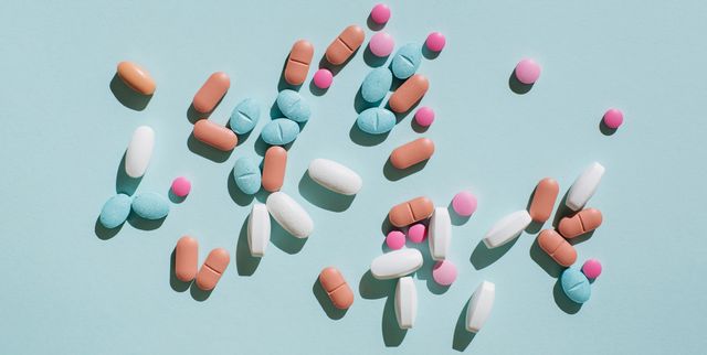 colorful pills and capsules on blue background minimal medical concept flat lay, top view