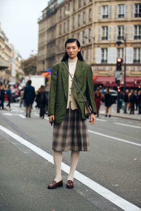 paris, france   september 28 model jiang fang lei  wears a green blazer, white garden, blue pleated print skirt, white stockings, and brown loafers after the balmain show during paris fashion week springsummer 2019 on september 28, 2018 in paris, france photo by melodie jenggetty images