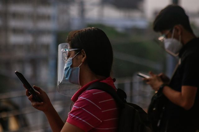 dos hombres miran sus teléfonos móviles durante la pandemia de coronavirus