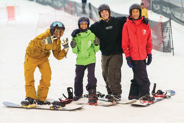 four people on snowboards looking at the camera