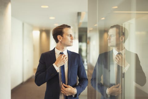 Confident businessman adjusting tie in office corridor