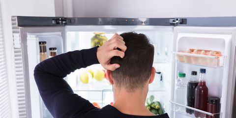 Confused Man Looking At Food In Refrigerator