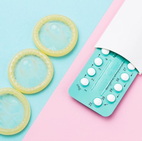 Contraceptive pills and condoms on colored background