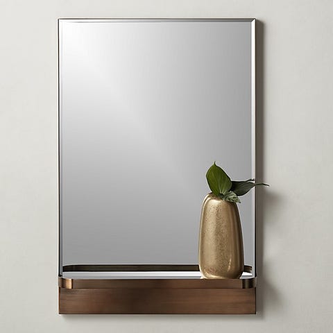 copper mirror with metallic vase on storage