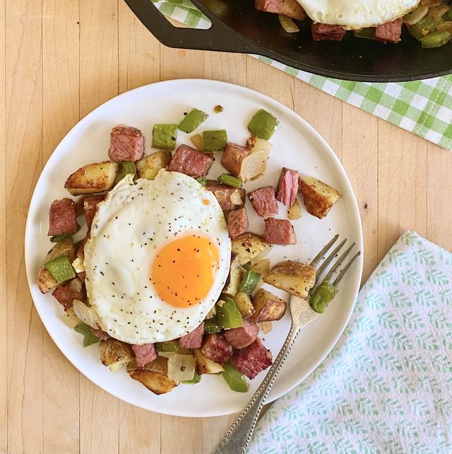 the pioneer woman's corned beef hash on a plate and in a skillet