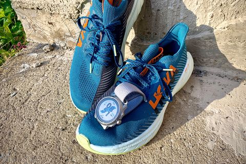 coros watch on top of running shoes on a sidewalk