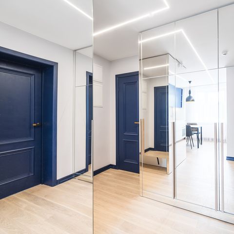 hal met spiegelkast en blauwe deur