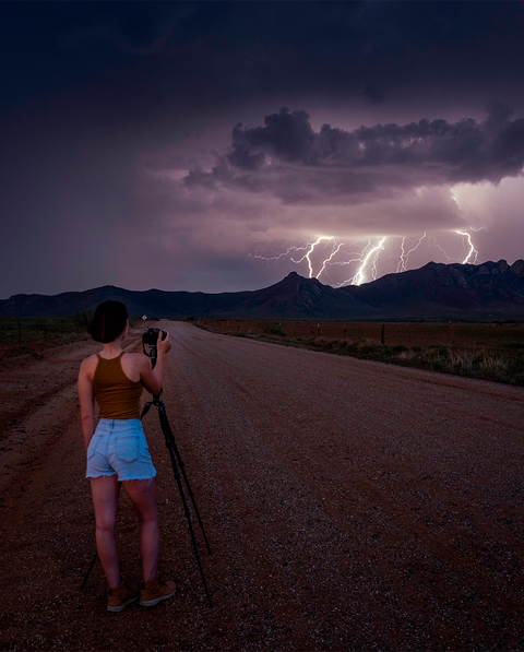 woman shooting lightning hitting a mountain from a distance