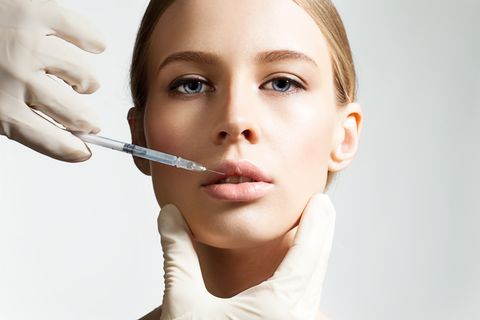 cosmetologist making botox injection in lips
