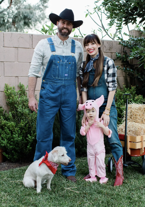 parents dressed as farmers in overalls and plaid shirts and toddler dressed as pig with dog wearing red bandana