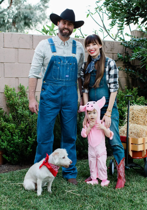 parents dressed as farmers in overalls and plaid shirts and toddler dressed as pig with dog wearing red bandana