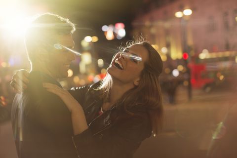 Couple hugging on city street at night