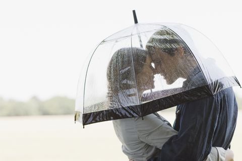 couple in rain hugging underneath umbrella