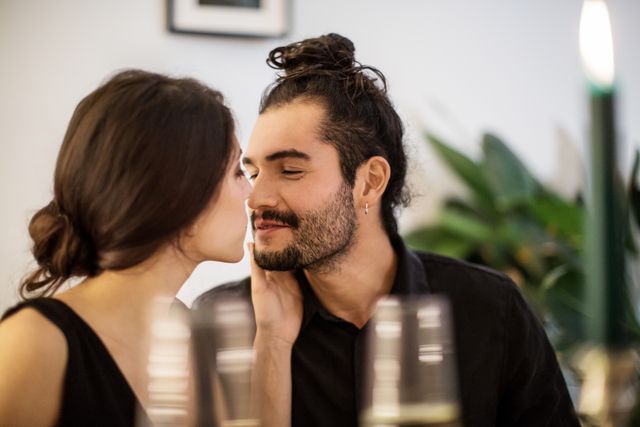 couple kissing during dinner party at home