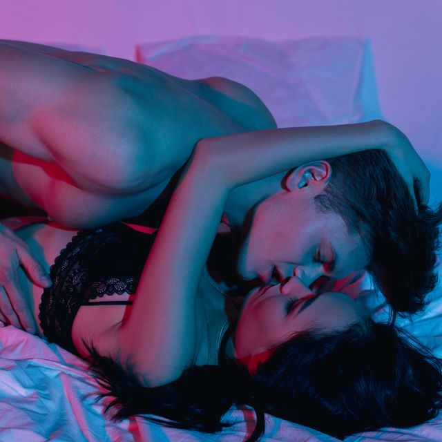 couple kissing in bed and holding condom