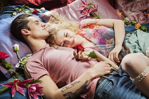 Couple laying on bed surrounded by flowers.