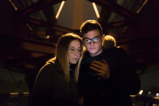 Paar kijkt naar mobiele telefoon onder een metalen brug