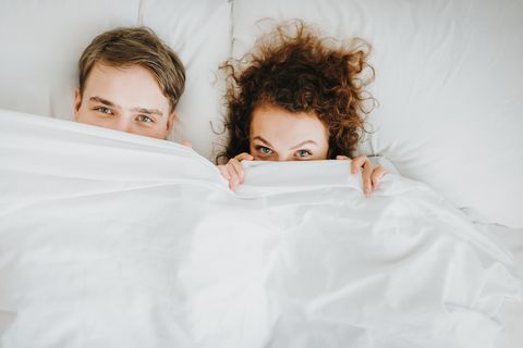 couple lying and hiding under white blanket