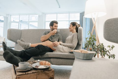 Couple relaxing on couch at home having breakfast