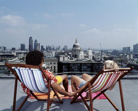 couple sitting in deck chairs and holding hands facing a skyline of london