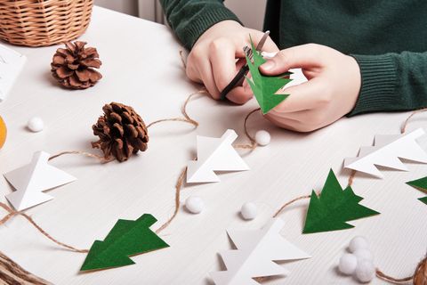 diy christmas home decor from natural materials hands make garland of paper trees, twine and cones