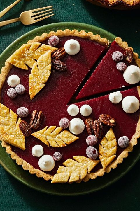 cranberry curd tart with pie leaves, cranberries and whipped cream on top