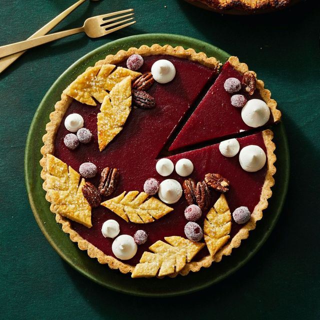 cranberry curd tart with pie leaves, cranberries and whipped cream on top
