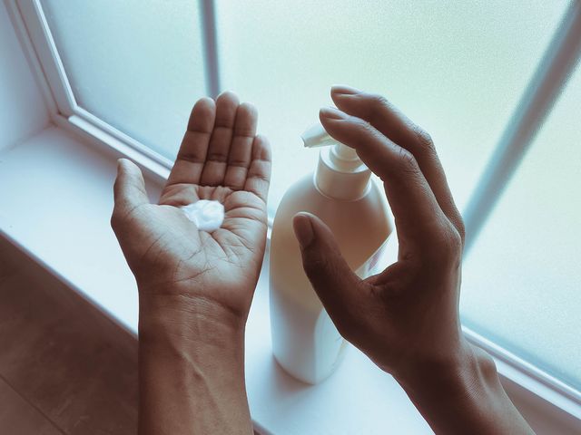 close up of unrecognizable woman pouring lotion into palm of her hand