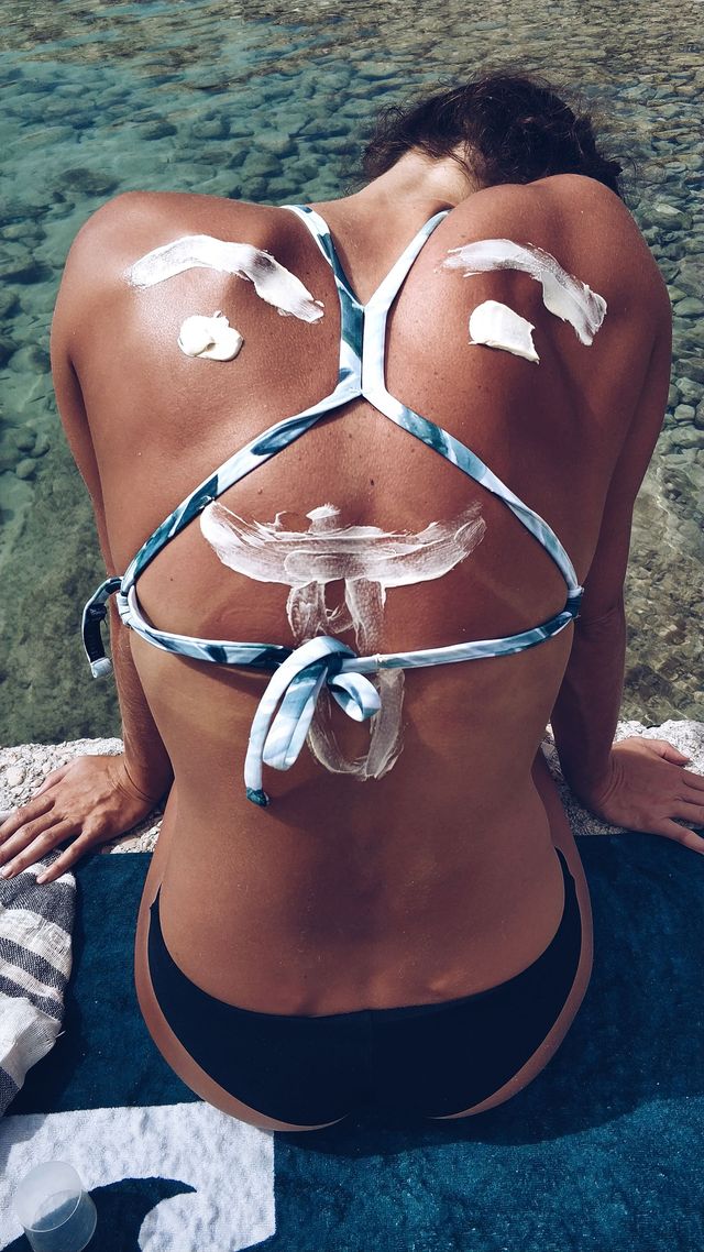 woman in bikinis with sun screen face drawn on her back