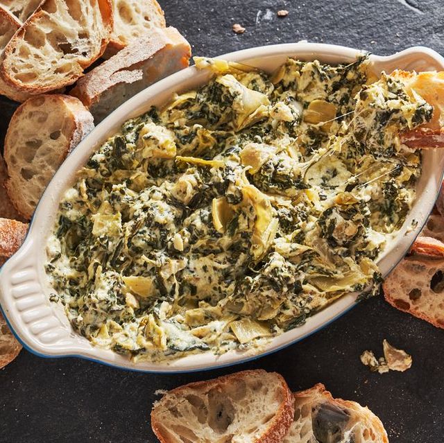 crockpot spinach and artichoke dip in a dish surrounded by bread slices