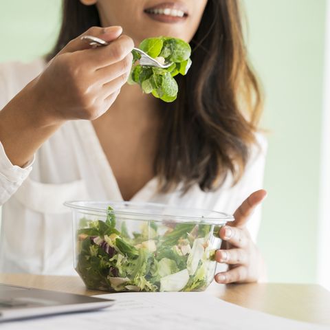 crop view of young architect eating mixed salad at desk