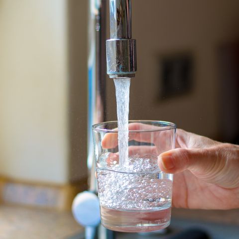 cropped hand filling glass with water from faucet