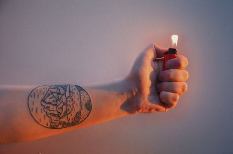 cropped hand holding illuminated cigarette lighter