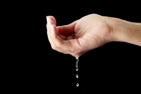 cropped hand holding water drop against black background