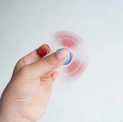 cropped hand of child playing with fidget spinner against white background