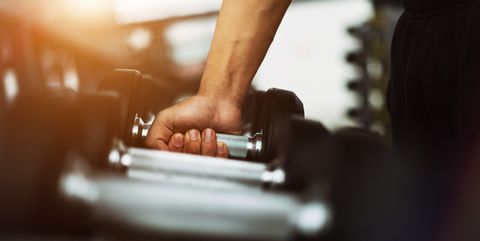 Cropped Hand Of Man Picking Barbell At Gym