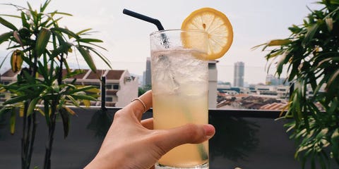 cropped hand of woman holding drink against sky