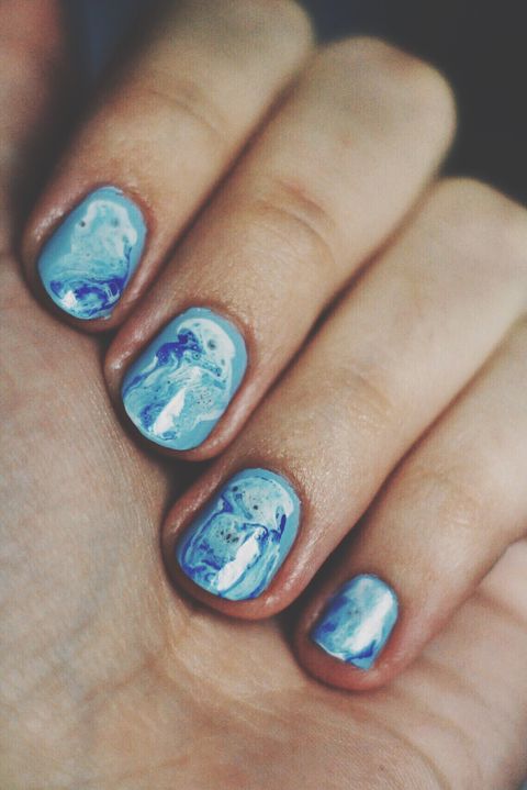 nails that are painted light blue and feature a dark blue marble design