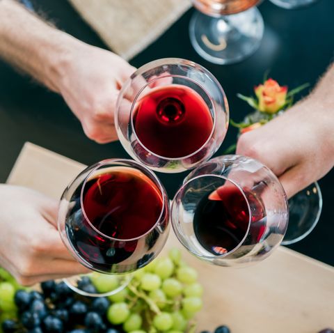 cropped hands of male friends toasting wine at tasting room