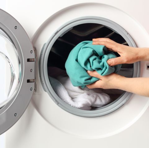 Cropped Hands Of Man Putting Clothes In Washing Machine At Home