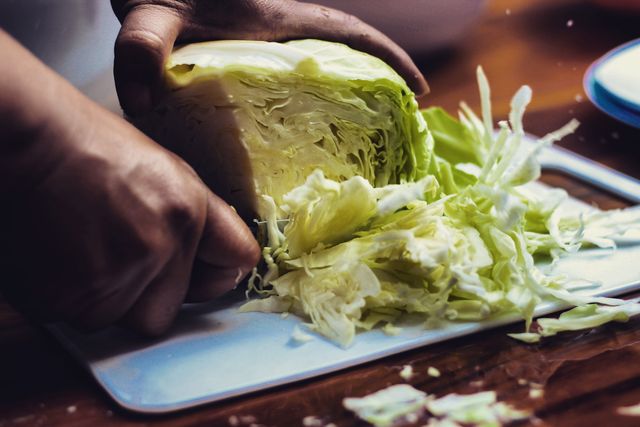cropped hands of person cutting cabbage on table