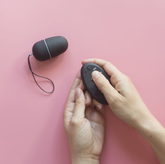 cropped hands of person holding remote control against pink background
