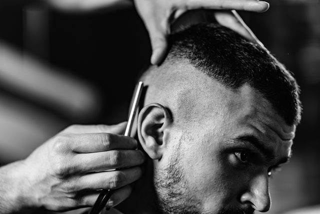 cropped image of barber cutting man hair in shop